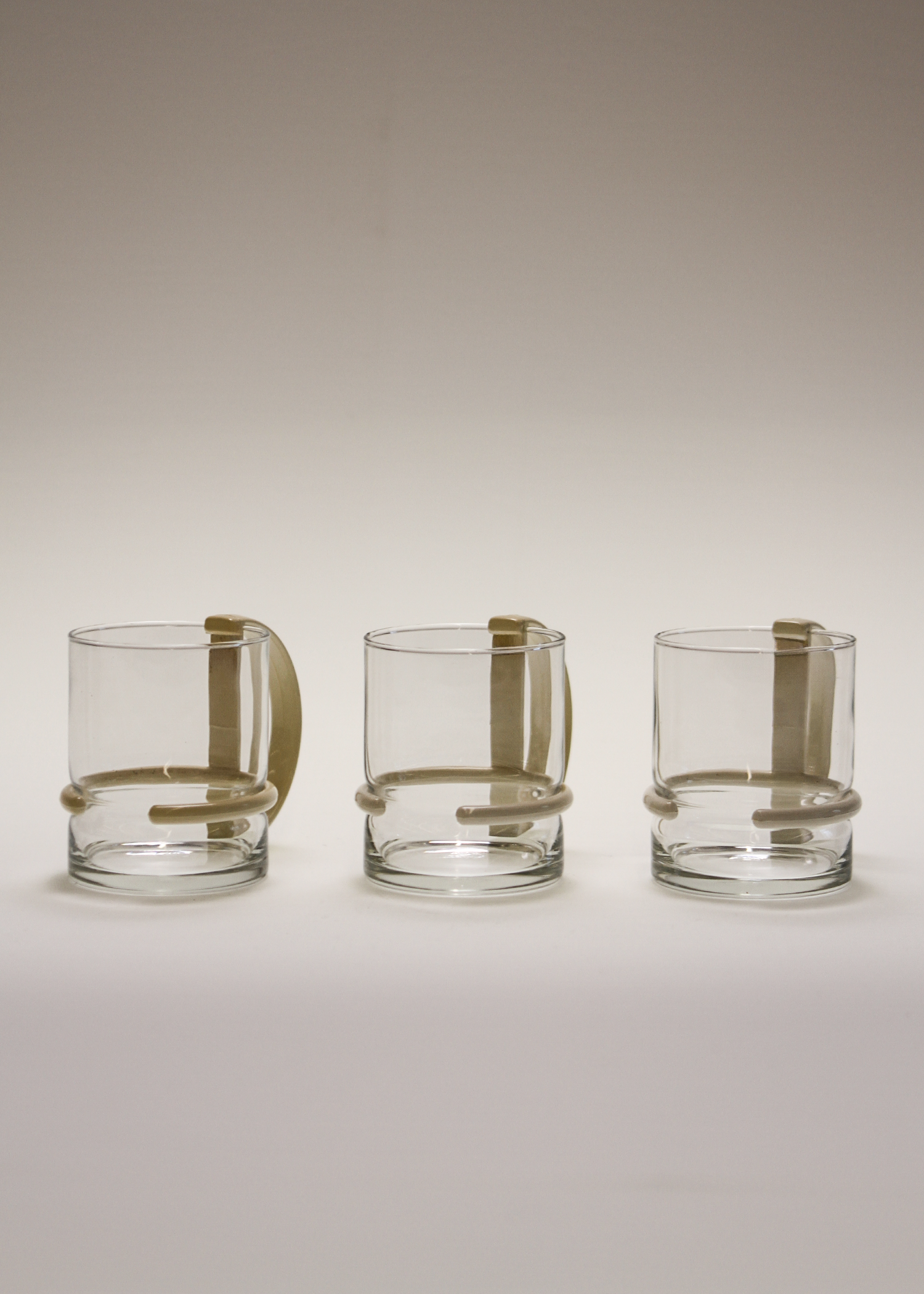 Set of three clear 1980s post modern glass mugs by inspiration made in italy vintage glassware featuring sculptural D-shaped black plastic handles, ideal for coffee or tea, minimalist silhouette. Available at In Corso, the curated marketplace for vintage furniture and objects at incorsostudio.com