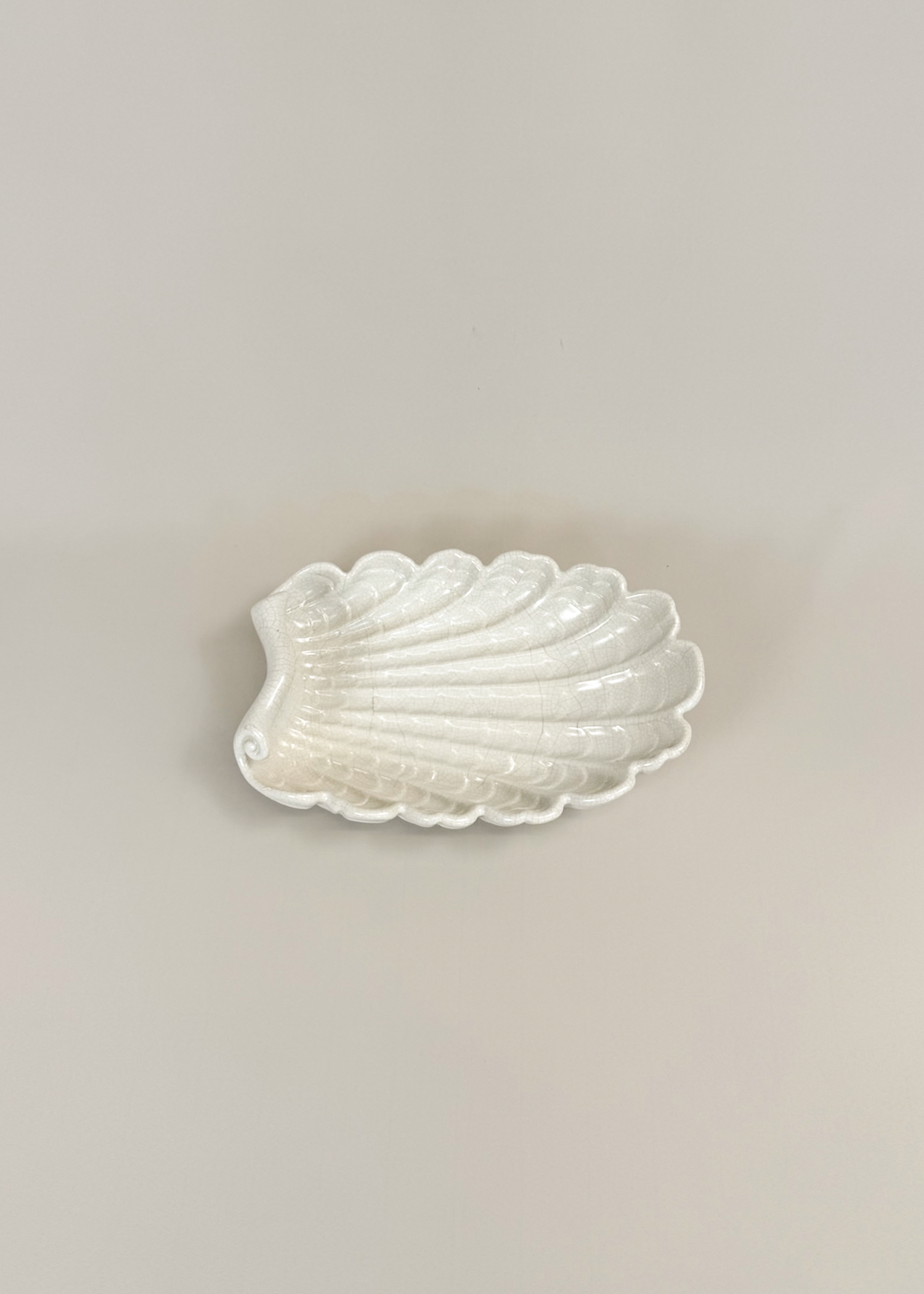 Vintage ceramic shell dish in matte white glaze with scalloped edges and organic wave contours. A decorative collectible for coastal, mid century or modern interiors perfect as a trinket tray or styling centerpiece.