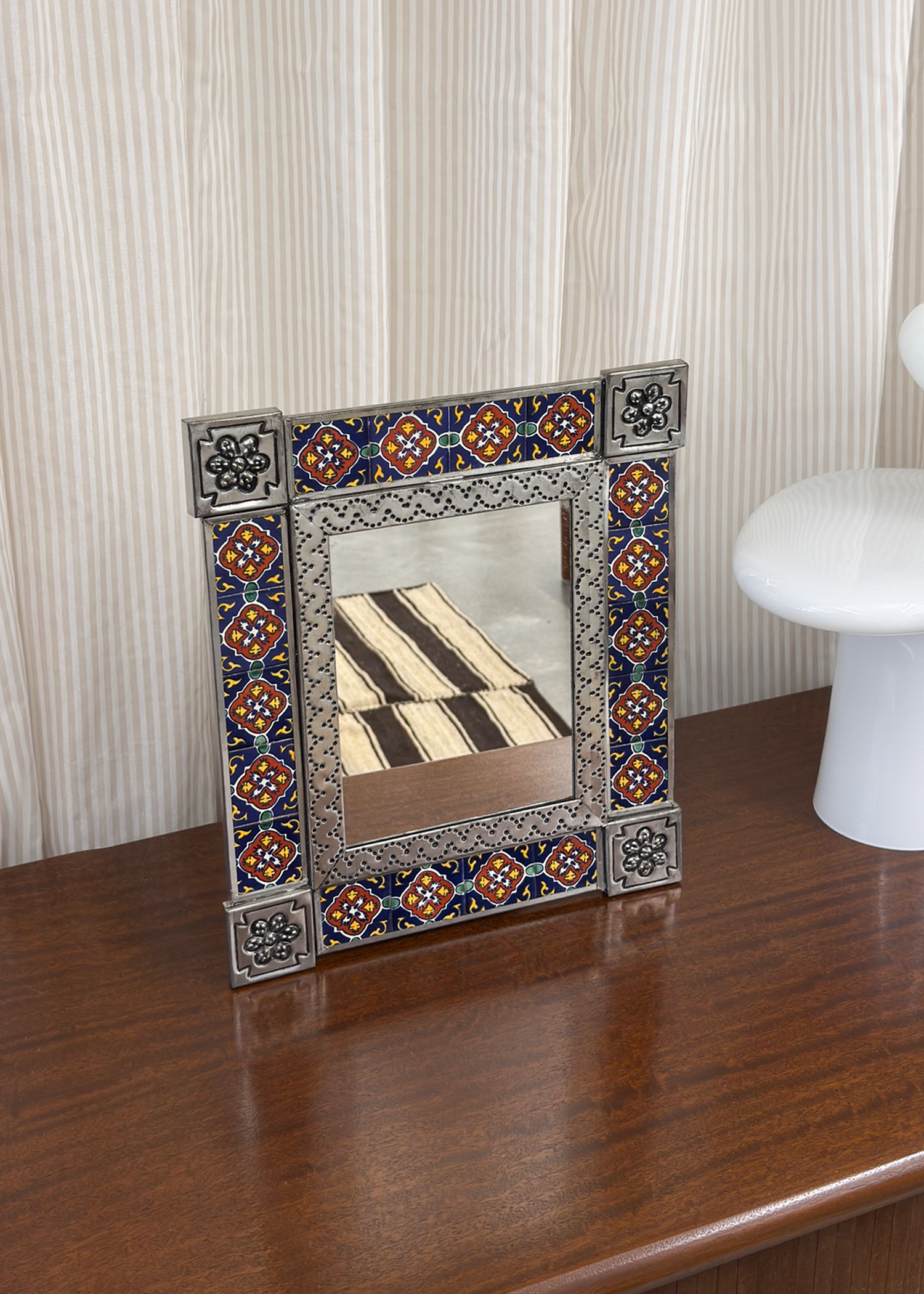 Punched tin Talavera tile mirror with painted Mexican motifs, aged patina on metal tin, 17 by 13 inches. A decorative vintage mirror combining Talavera tile art and punched tin for rustic artisan character