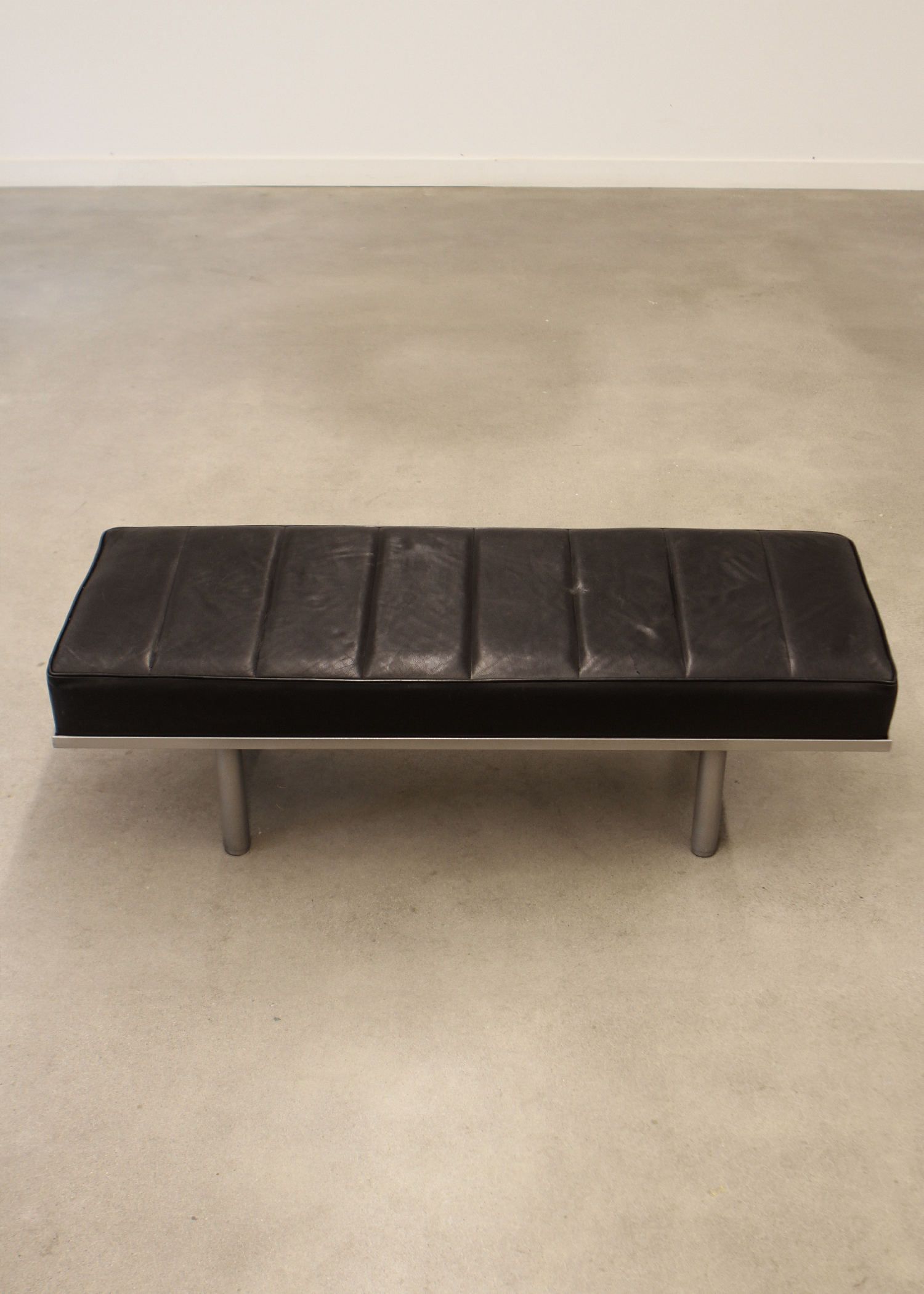 Black leather bench with tufted seat cushion and low profile frame, ideal for entryways or living rooms. Sold by In Corso Studio a vintage furniture company specializing in rare mid century furniture in Toronto Canada