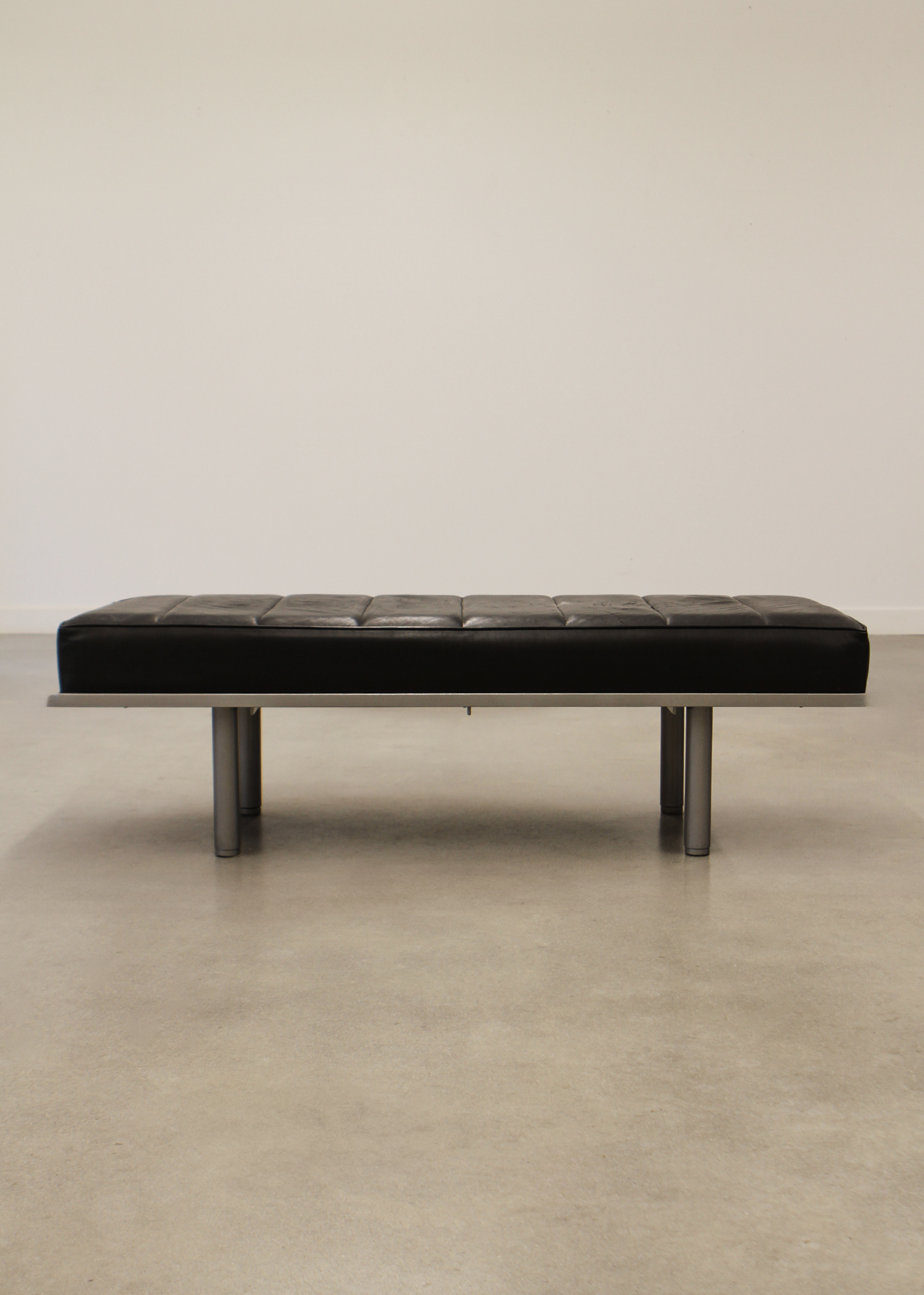 Black leather bench with tufted seat cushion and low profile frame, ideal for entryways or living rooms. Sold by In Corso Studio a vintage furniture company specializing in rare mid century furniture in Toronto Canada