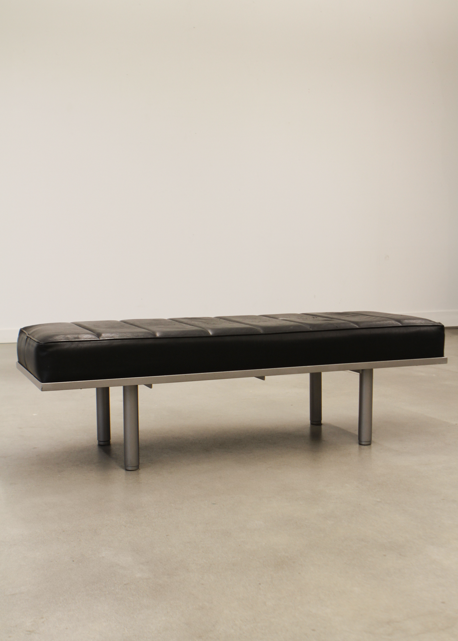 Black leather bench with tufted seat cushion and low profile frame, ideal for entryways or living rooms. Sold by In Corso Studio a vintage furniture company specializing in rare mid century furniture in Toronto Canada