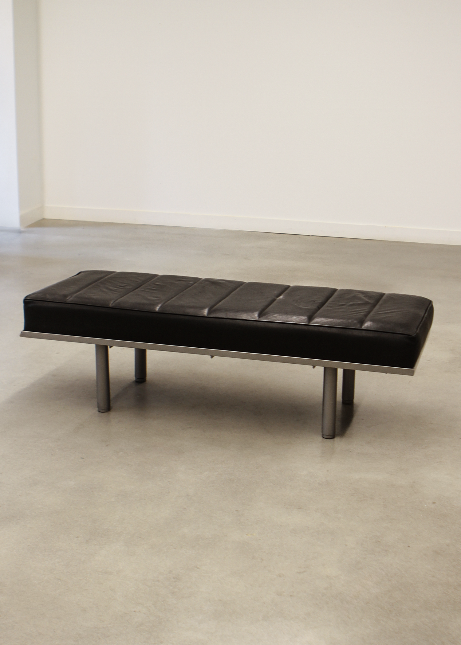 Black leather bench with tufted seat cushion and low profile frame, ideal for entryways or living rooms. Sold by In Corso Studio a vintage furniture company specializing in rare mid century furniture in Toronto Canada