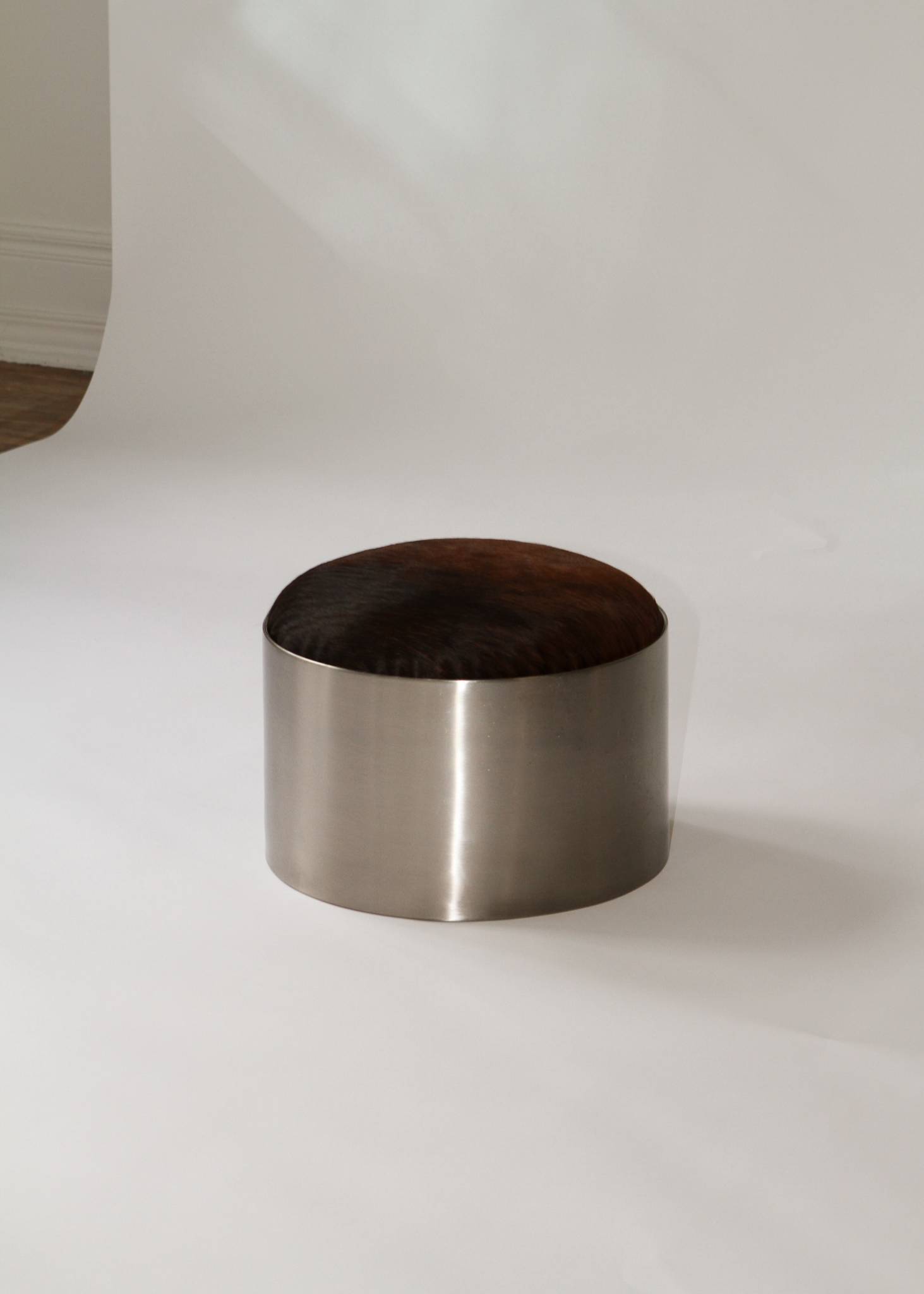 Cylindrical foot stool with leather cowhide pony hair top and chrome base on a white background - available on incorsostudio.com 