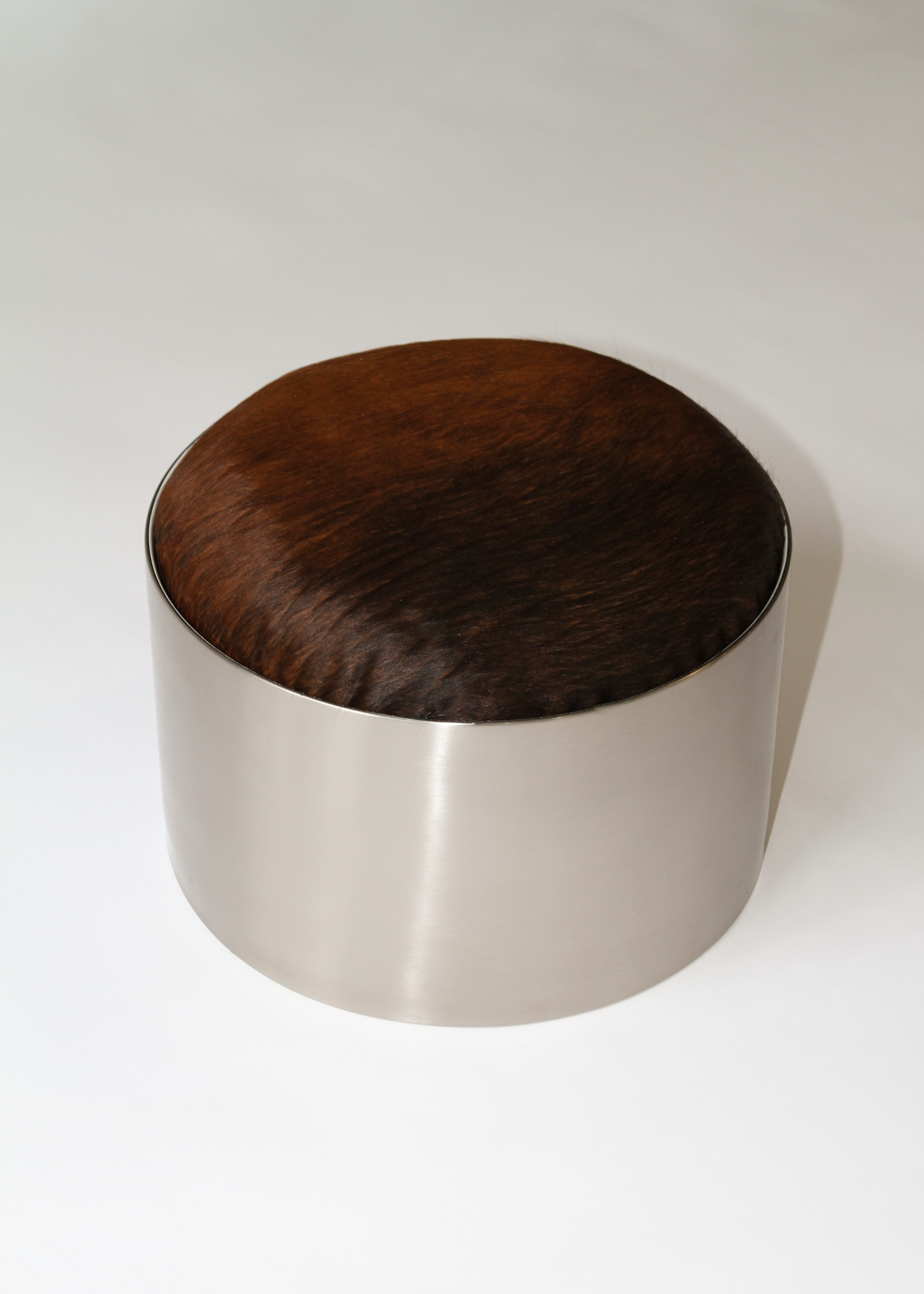 Cylindrical foot stool with leather cowhide pony hair top and chrome base on a white background - available on incorsostudio.com 