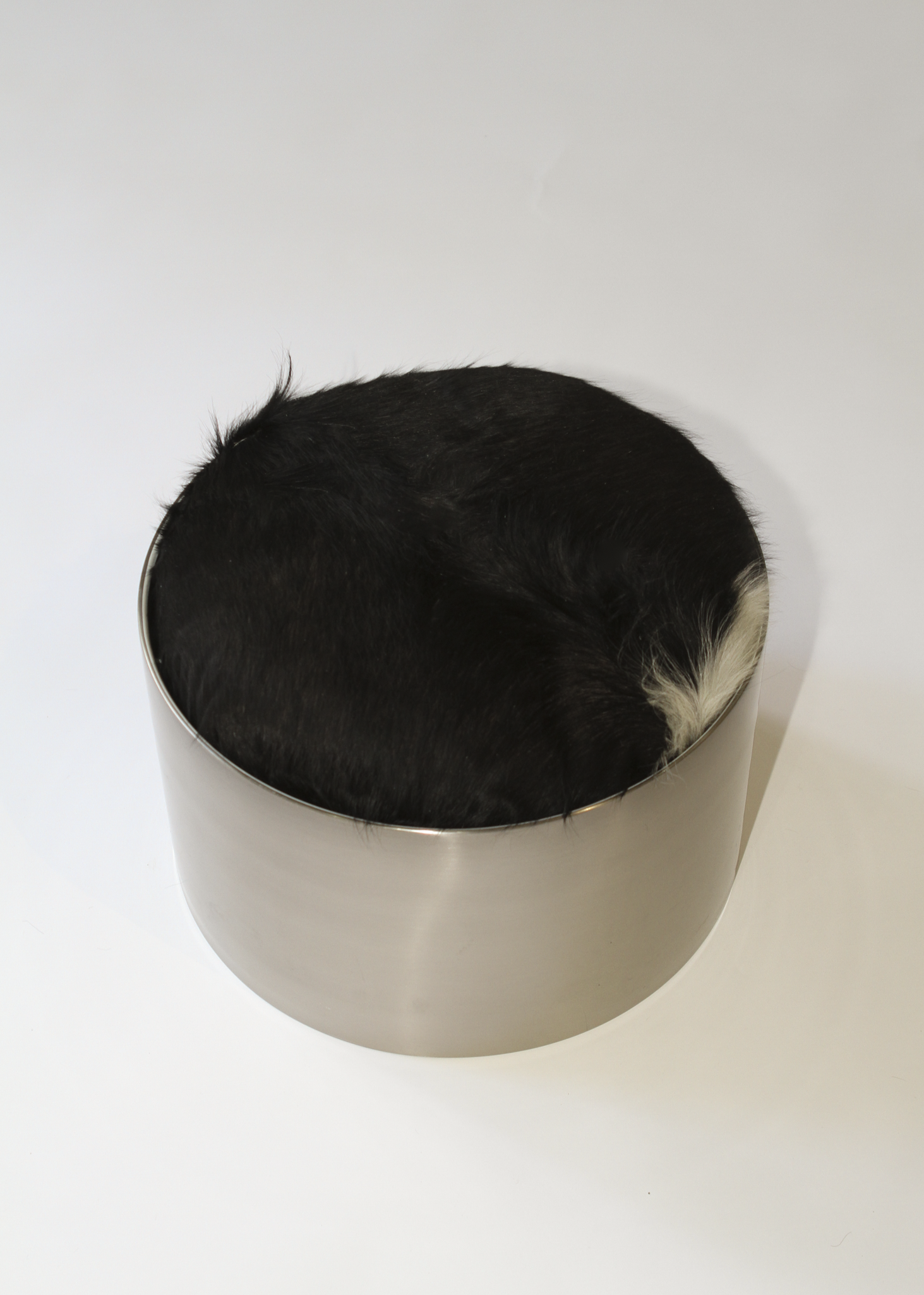 Cylindrical foot stool with leather cowhide pony hair top and chrome base on a white background - available on incorsostudio.com 