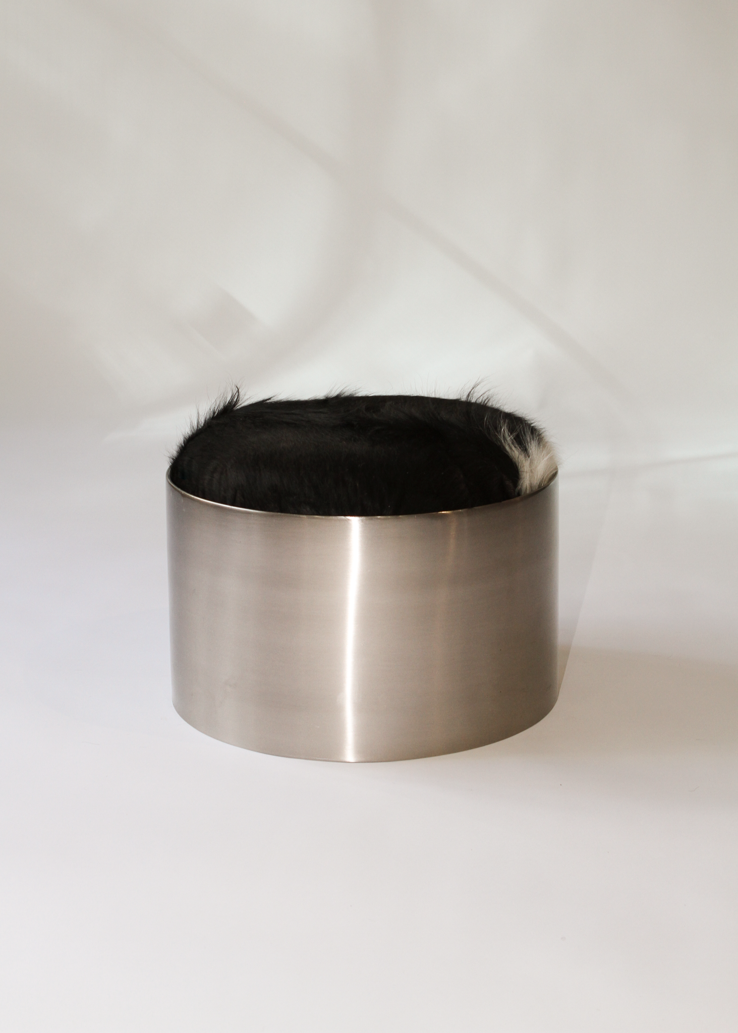 Cylindrical foot stool with leather cowhide pony hair top and chrome base on a white background - available on incorsostudio.com 