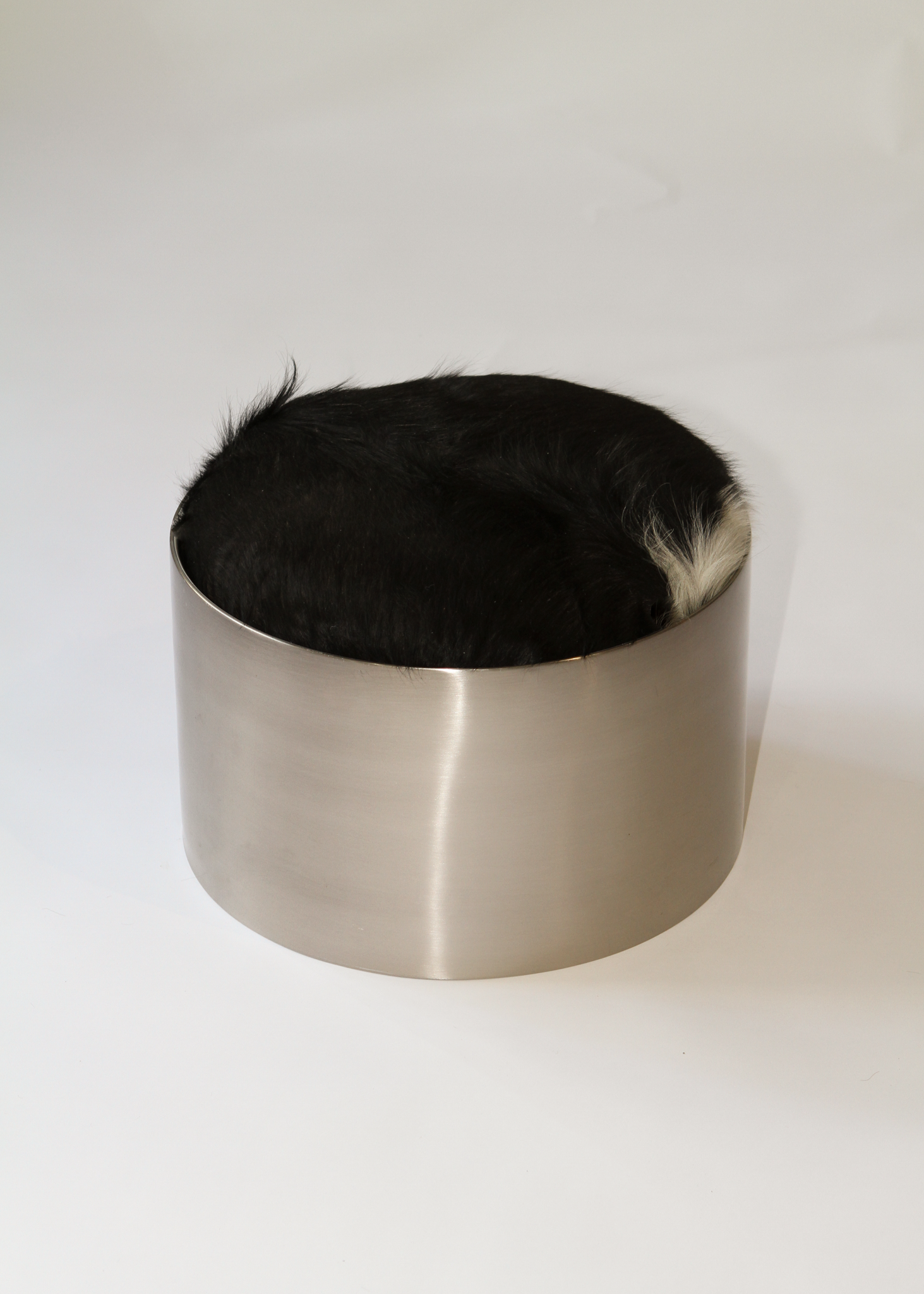 Cylindrical foot stool with leather cowhide pony hair top and chrome base on a white background - available on incorsostudio.com 