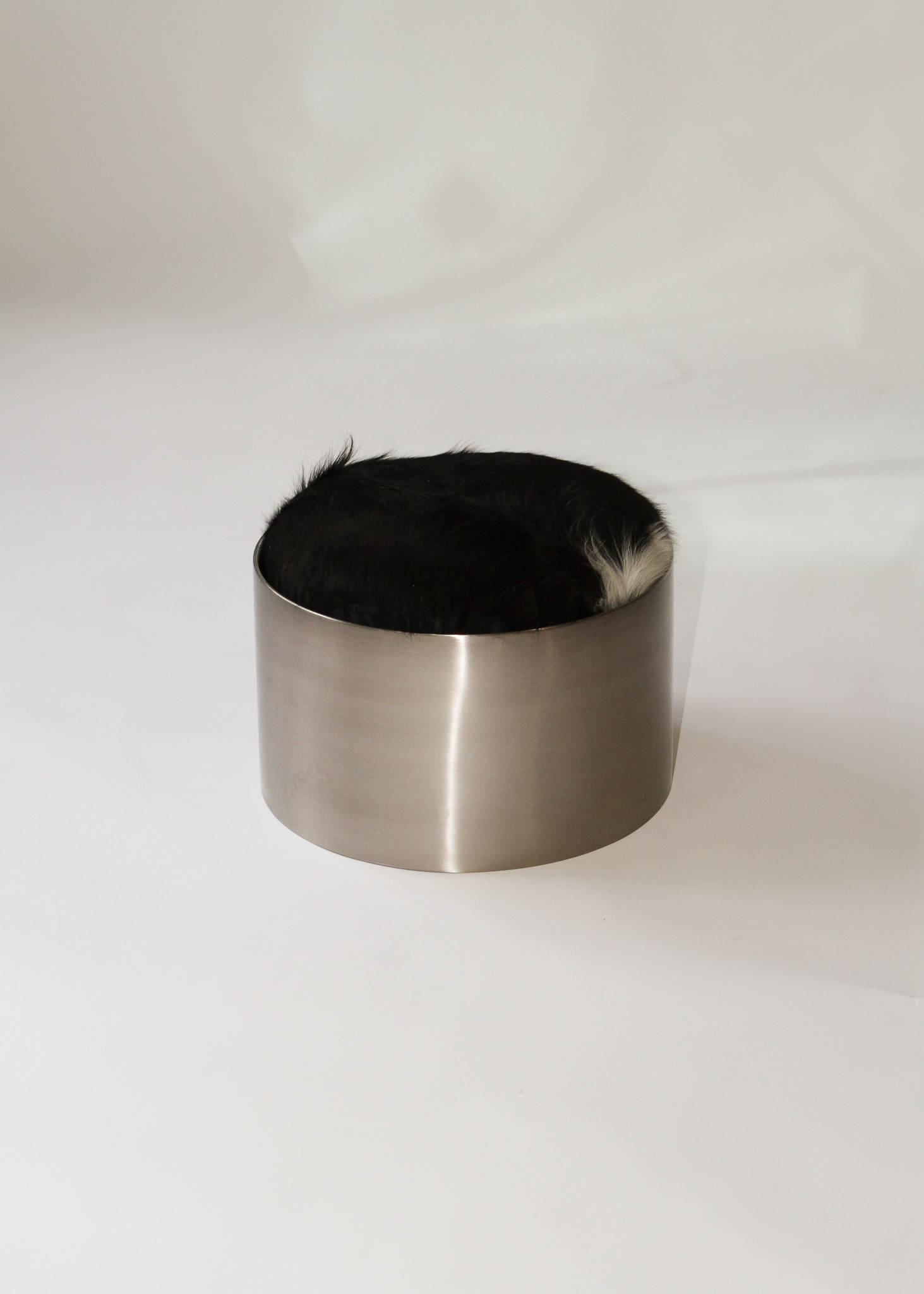Cylindrical foot stool with leather cowhide pony hair top and chrome base on a white background - available on incorsostudio.com 