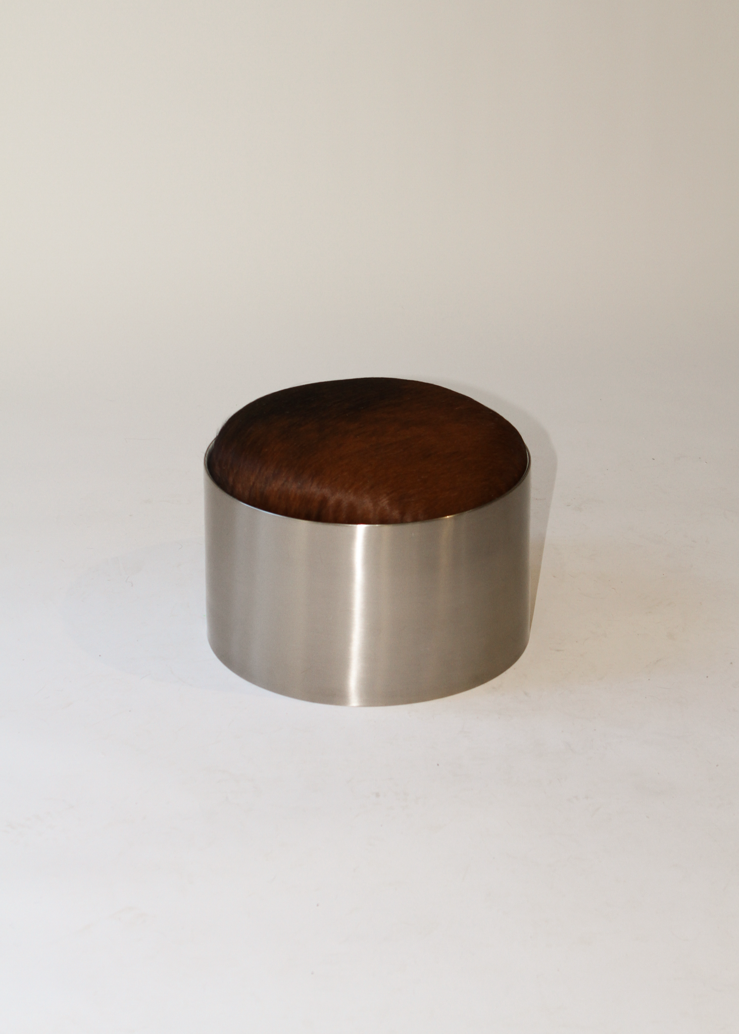 Cylindrical foot stool with leather cowhide pony hair top and chrome base on a white background - available on incorsostudio.com 