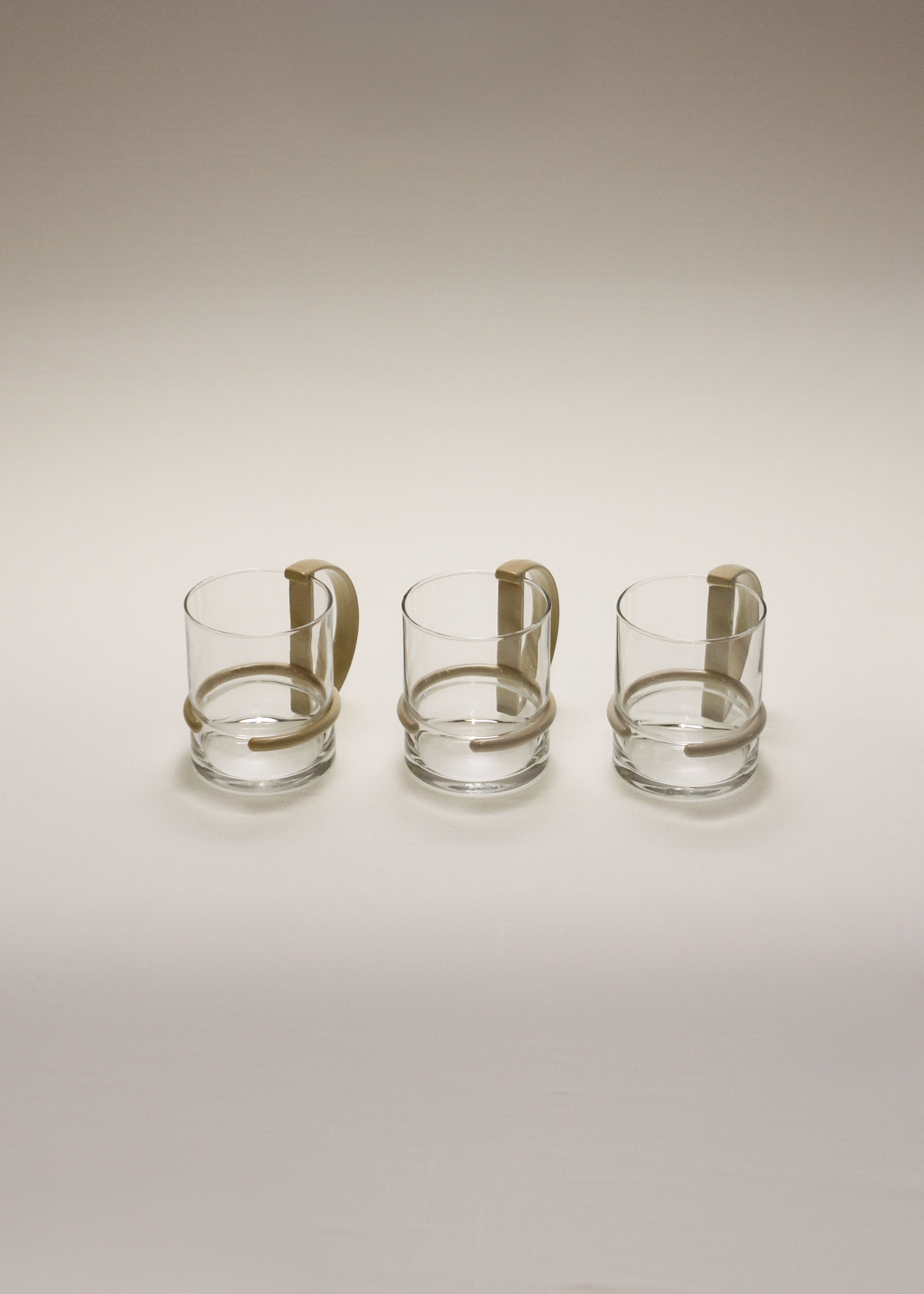 Set of three clear 1980s post modern glass mugs by inspiration made in italy vintage glassware featuring sculptural D-shaped black plastic handles, ideal for coffee or tea, minimalist silhouette. Available at In Corso, the curated marketplace for vintage furniture and objects at incorsostudio.com