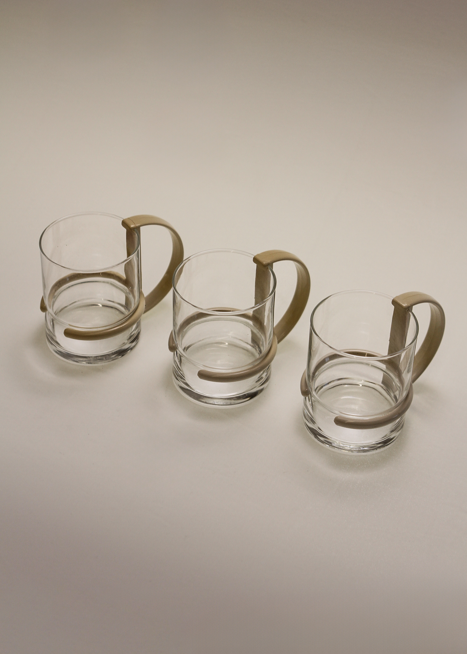 Set of three clear 1980s post modern glass mugs by inspiration made in italy vintage glassware featuring sculptural D-shaped black plastic handles, ideal for coffee or tea, minimalist silhouette. Available at In Corso, the curated marketplace for vintage furniture and objects at incorsostudio.com