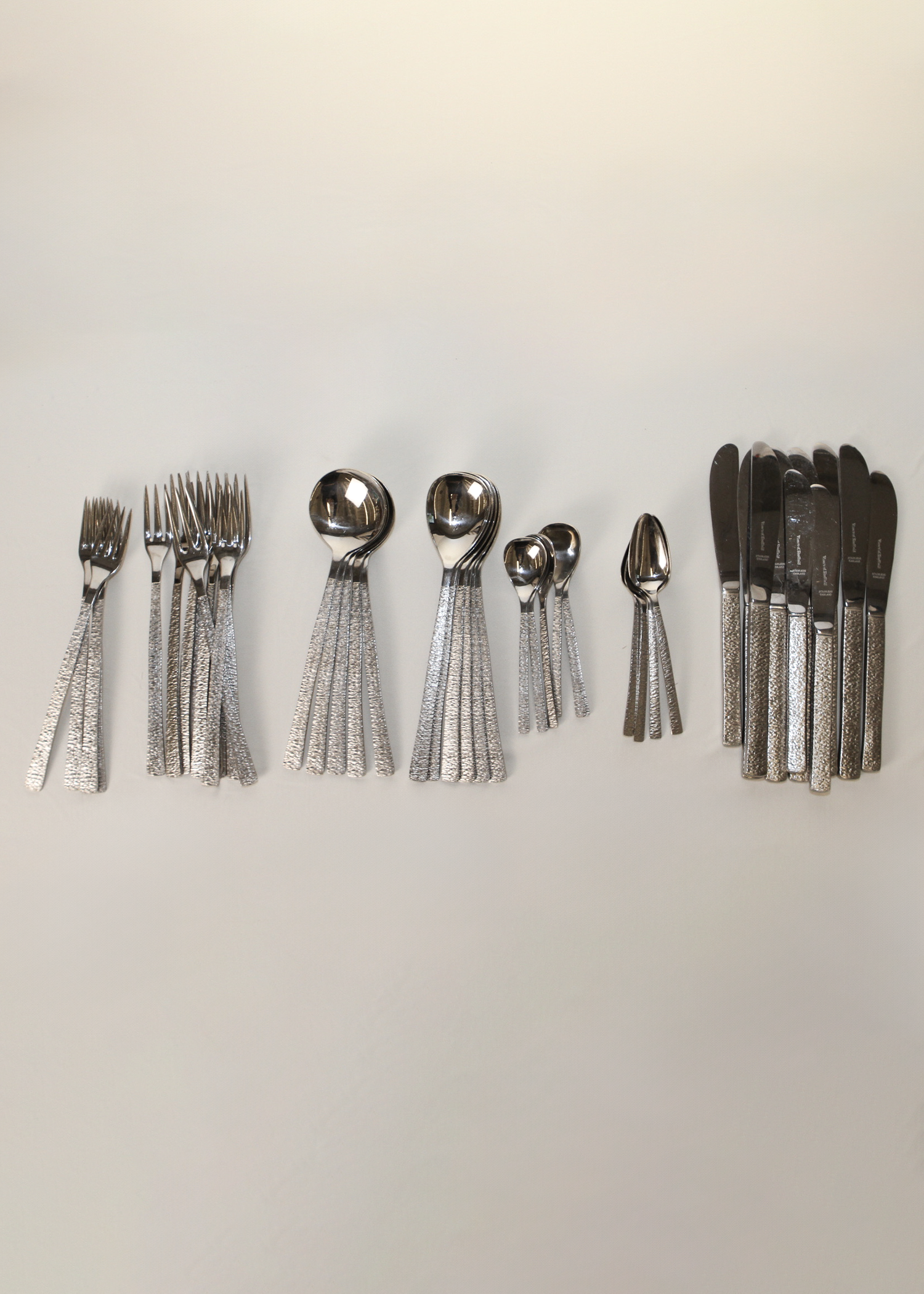 **Alt text:**
Set of 38-piece vintage flatware by Gerald Benney for Viners of Sheffield, elegantly arranged on a matte dark surface. Each piece features sleek, minimalist stainless steel construction and subtle British hallmarks, showcasing post-war modern design. Available at In Corso, Toronto’s marketplace for vintage and modern design.
