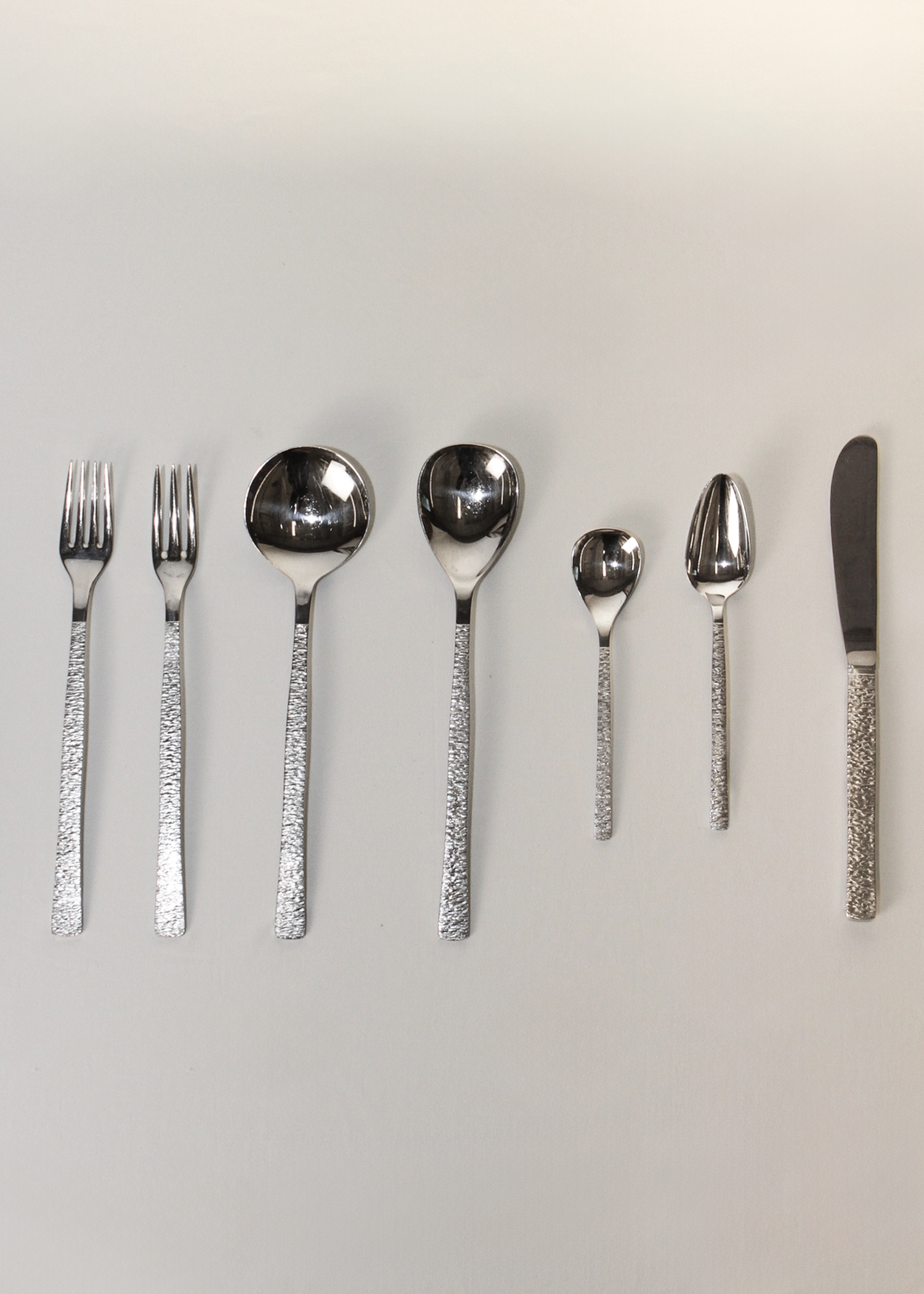**Alt text:**
Set of 38-piece vintage flatware by Gerald Benney for Viners of Sheffield, elegantly arranged on a matte dark surface. Each piece features sleek, minimalist stainless steel construction and subtle British hallmarks, showcasing post-war modern design. Available at In Corso, Toronto’s marketplace for vintage and modern design.
