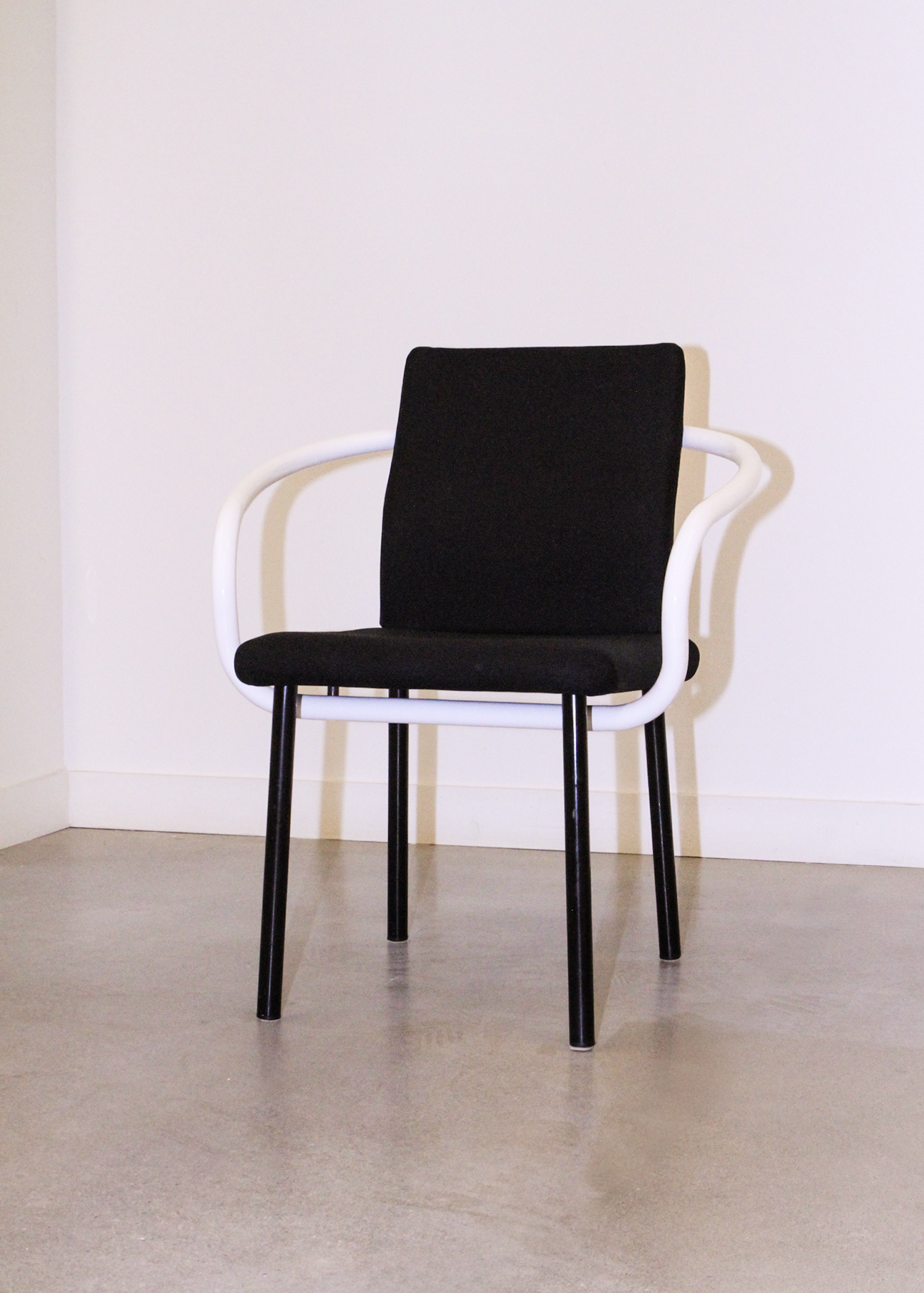 Pair of vintage Mandarin chairs by Ettore Sottsass for Knoll in black upholstery with sculptural white tubular arms. Collectible postmodern designer seating from 1986, perfect for mid century modern inspired interiors