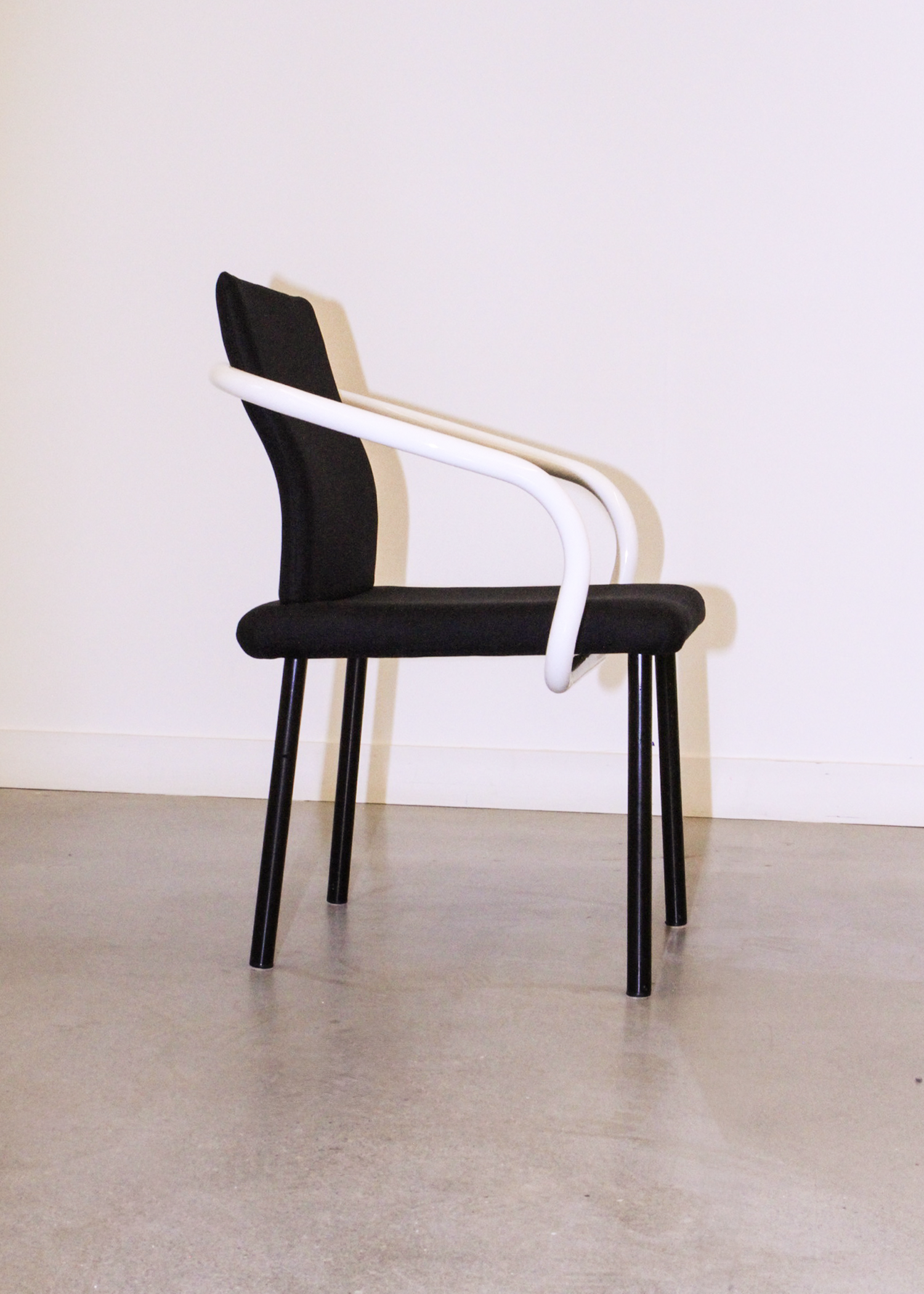 Pair of vintage Mandarin chairs by Ettore Sottsass for Knoll in black upholstery with sculptural white tubular arms. Collectible postmodern designer seating from 1986, perfect for mid century modern inspired interiors